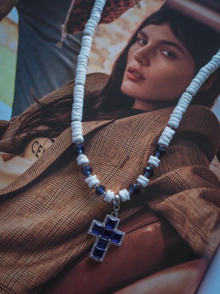 Artistic display of a cross pendant necklace on a fashion magazine page.