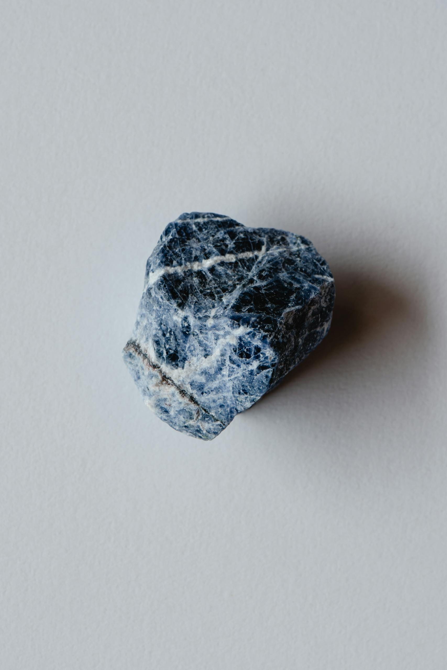Detailed close-up of a sodalite rock, showcasing natural texture on a neutral backdrop.